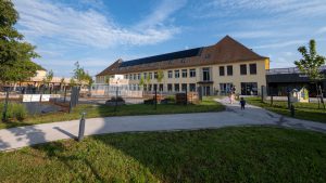 photo d'une école, premier plan la cour réaménagée avec beaucoup de verdure